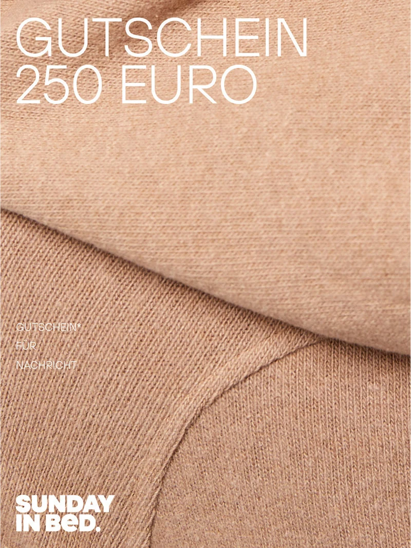 Gutschein im Wert von 250 Euro wird durch ein beiges Kleidungsstück dargestellt. Es ist sehr nah zu sehen und eine große Falte in der Mitte. Oben, links in der Ecke steht in weißen Großbuchstaben „GUTSCHEIN 250 EURO“.